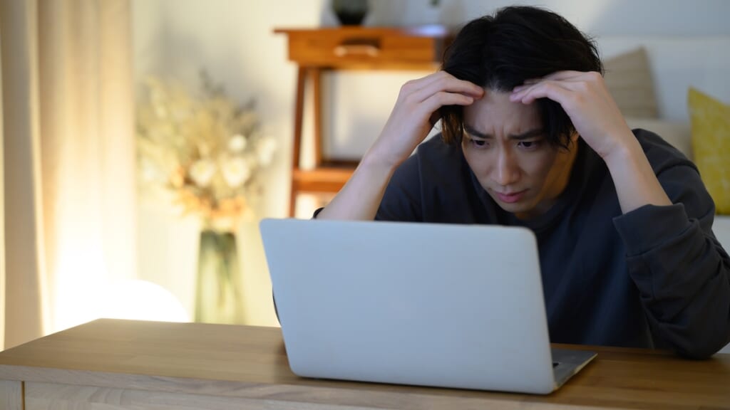 PCの前で頭を抱える男性