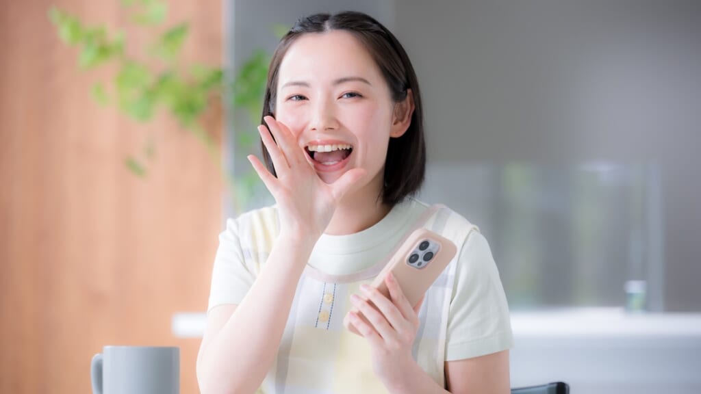 スマホを持ちこちらに声をかける様子の女性