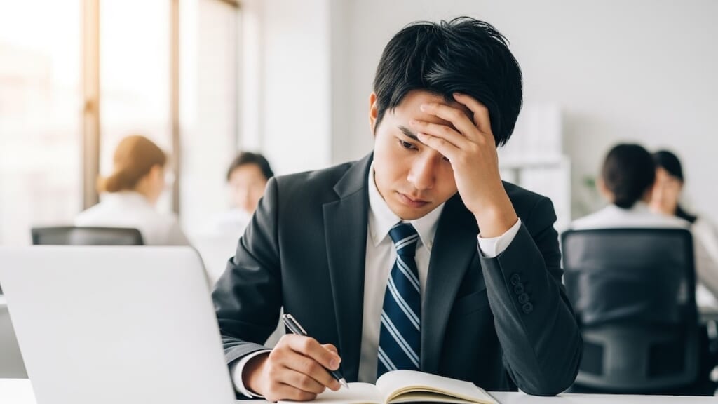 PC作業しながら悩む男性会社員