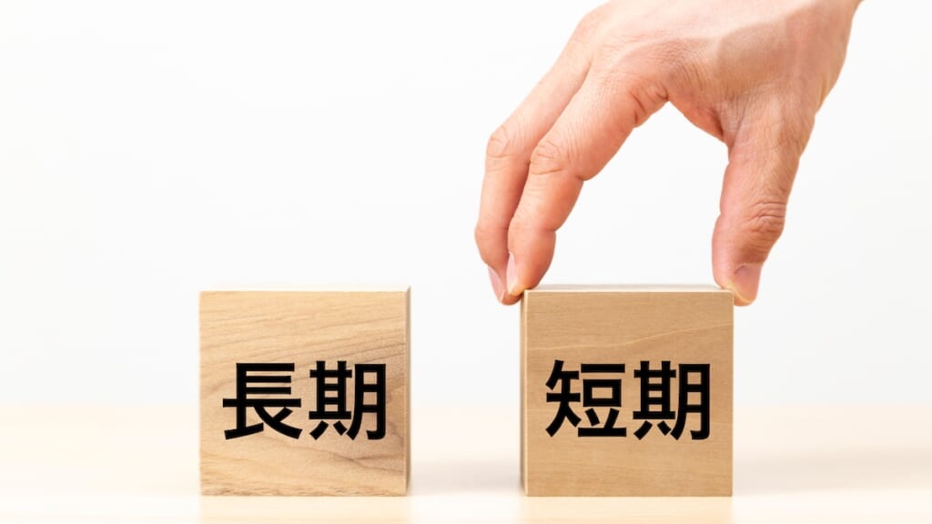 短期と書かれた積木をもつ手